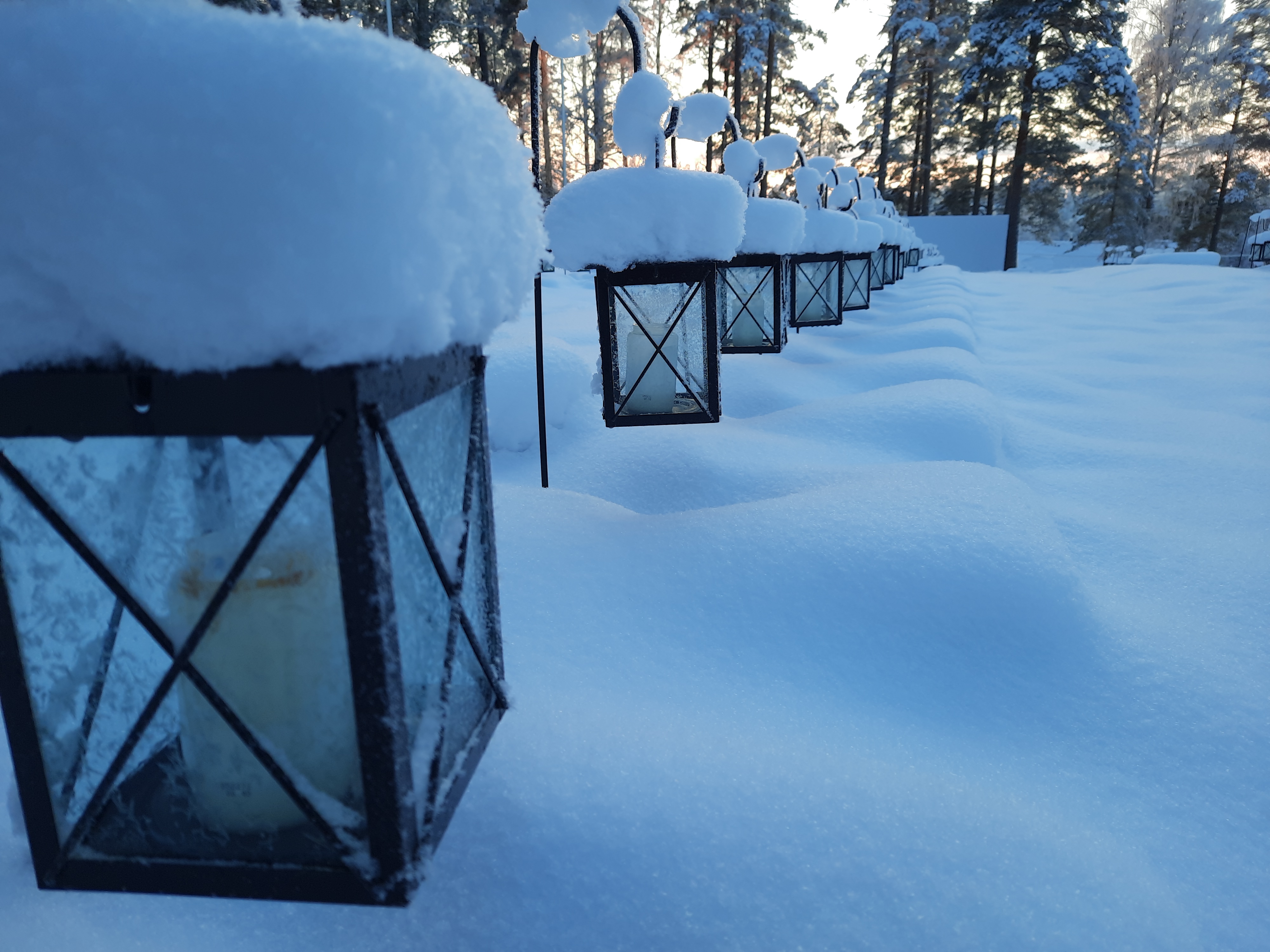 Lumisia lyhtyjä Keiteleen sankarihautausmaalla.