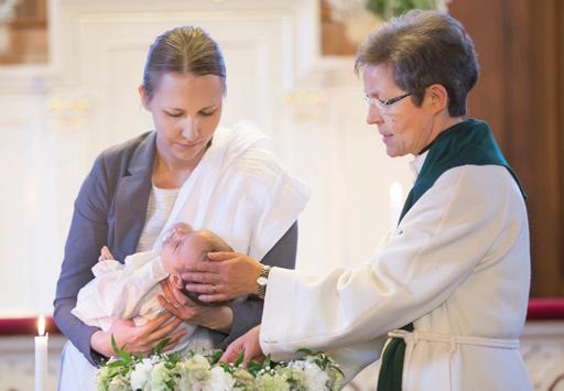 Pappi kastaa kummin sylissä olevaa lasta.