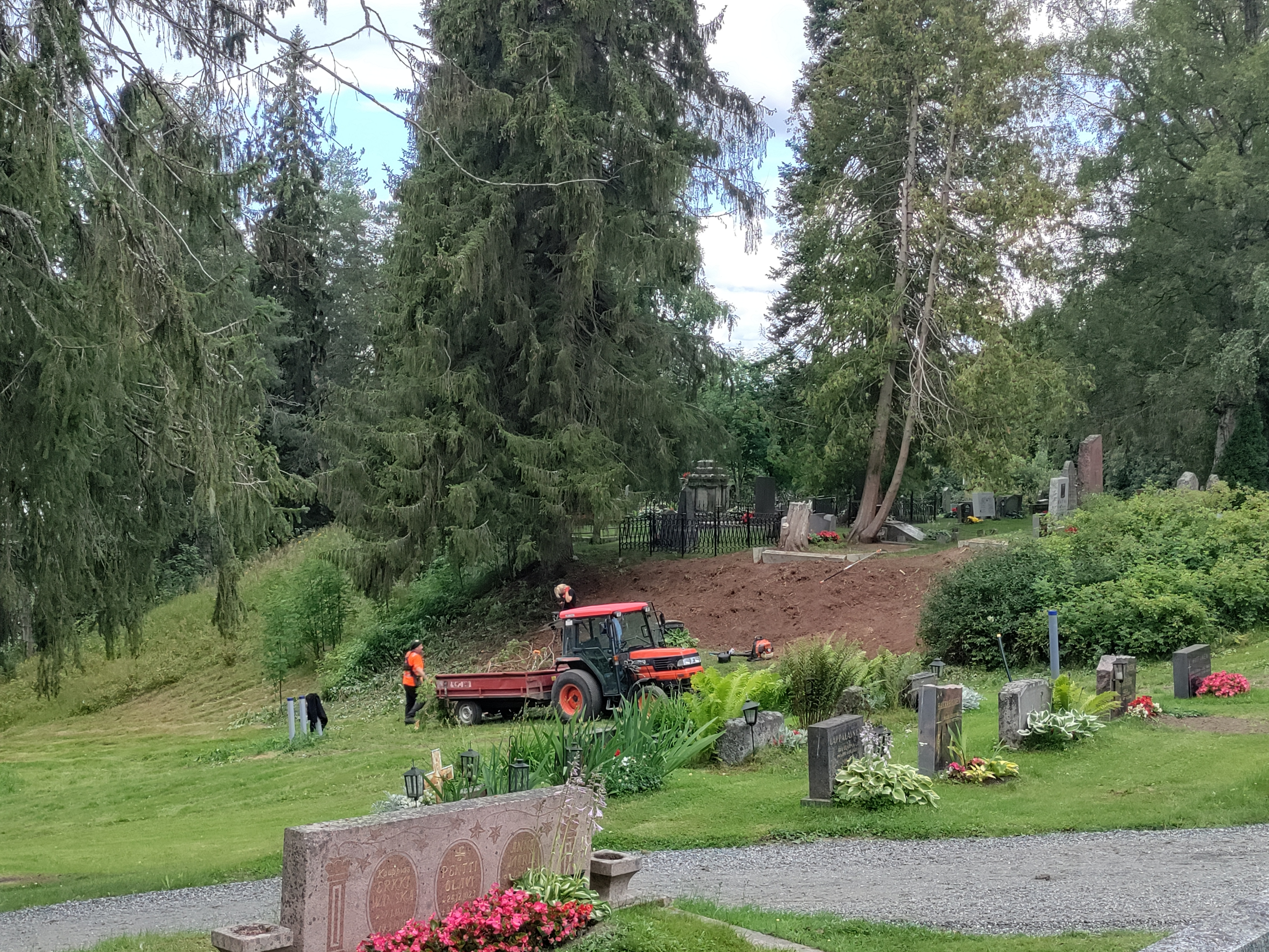 Traktori ja työntekijöitä Iisalmen Vanhalla hautausmaalla töissä kesäaikaan.