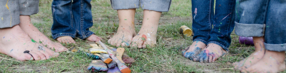 Maassa pensseleitä. Lasten jaloissa maalia.